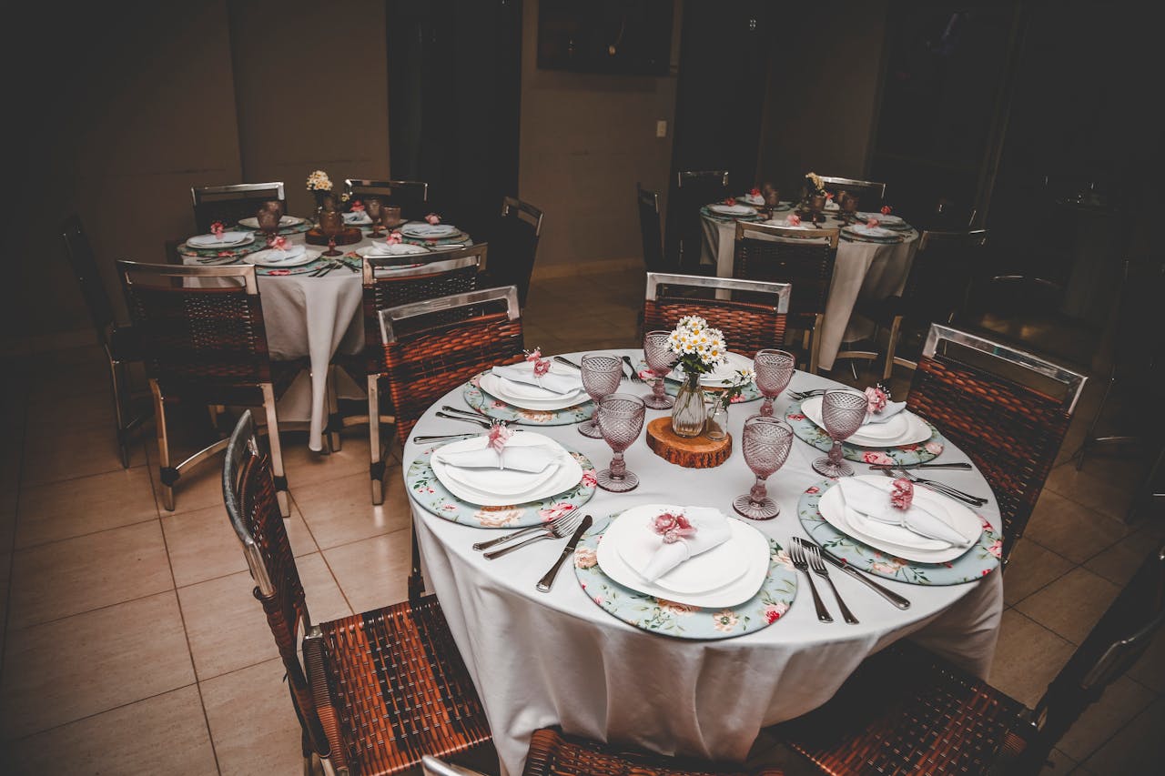 Beautifully decorated dining tables with floral plates at an indoor wedding reception.